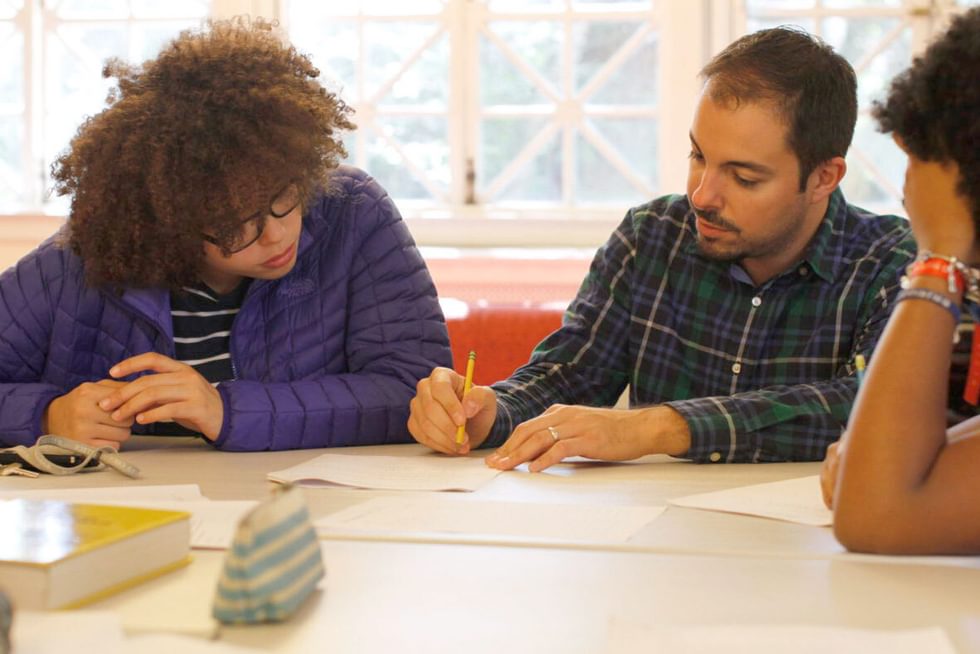 Two students and a professor work together at a table