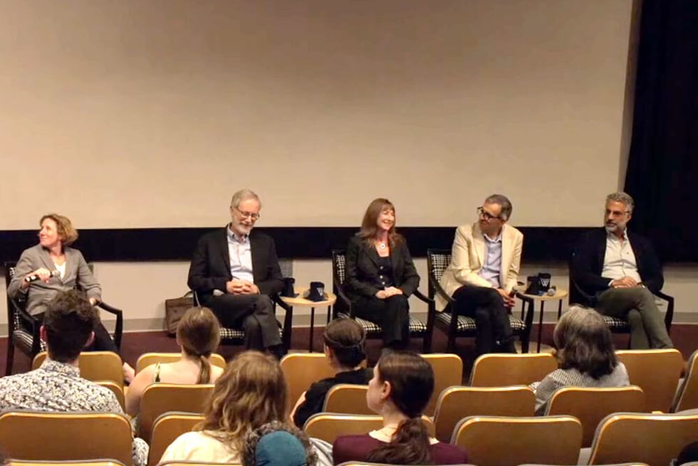 Five panelists seated chairs in front of an audience