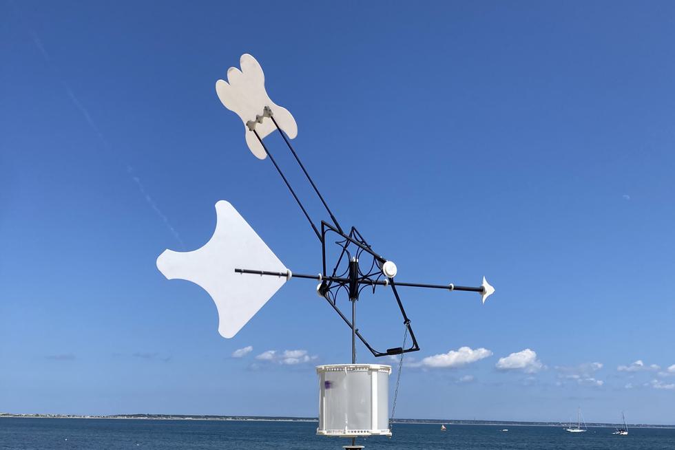 A metal contraption with an arrow by the sea.