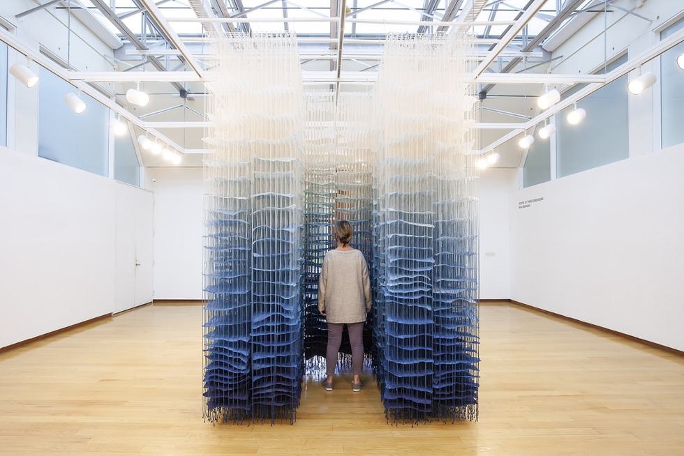A student stands in the middle of an interactive art piece in the Jewett Art Gallery.