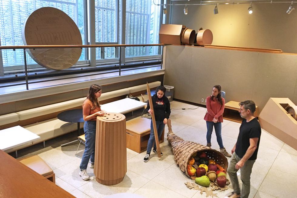 Three students and a professor install a sculpture shaped like a cornucopia into the Jewett Sculpture Court.