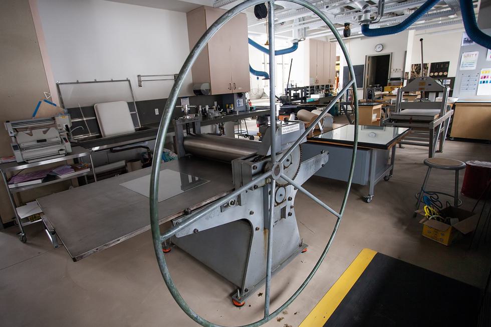 A modern printing press sits in the foreground of an empty Dactyl Press.