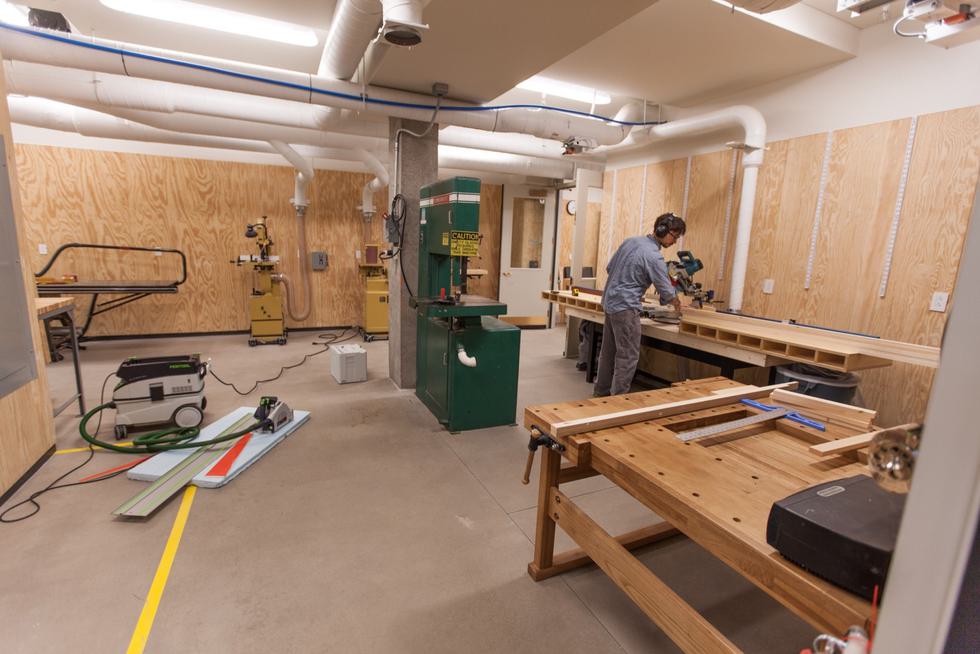 A student uses a chop saw in an otherwise empty wood shop.