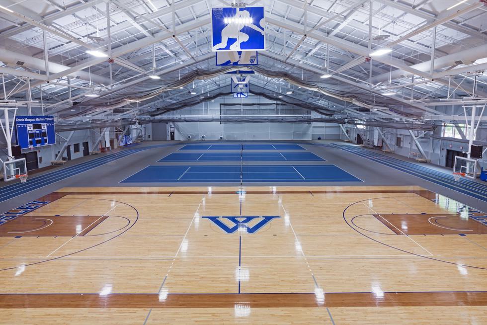 An empty basketball court with the Wellesley "W" logo painted in the center.