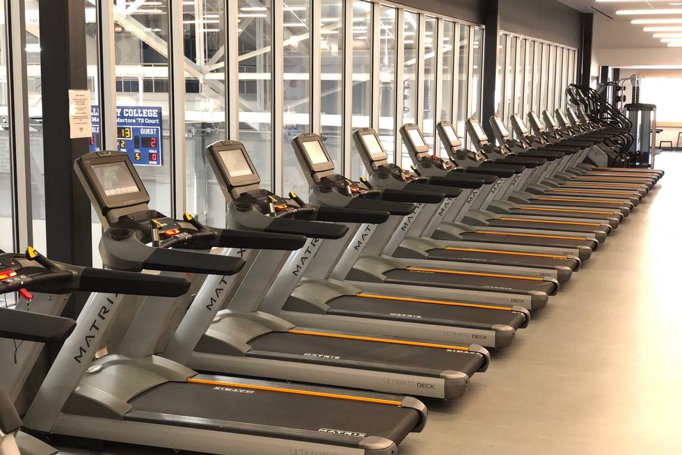 Row of empty treadmills inside fitness center.