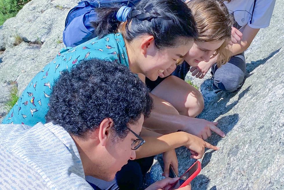 Professor Castro and students closely examine the details of an outdoor rock formation.