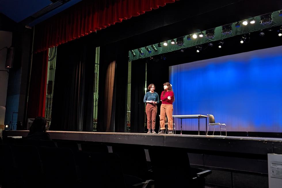 Two students stand on a stage.