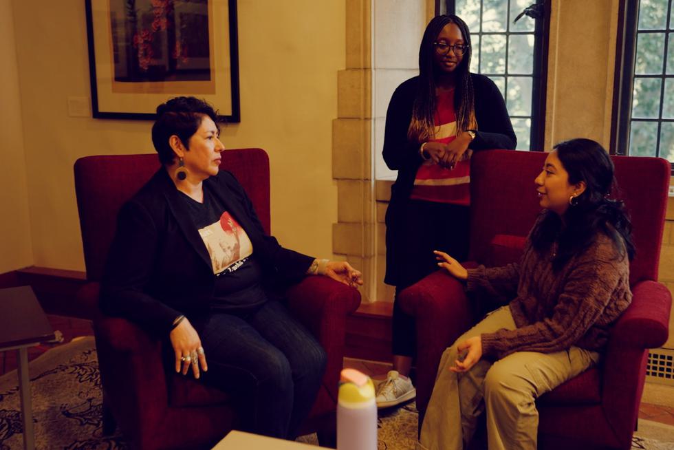 Two faculty members converse with a student in the Newhouse Center.