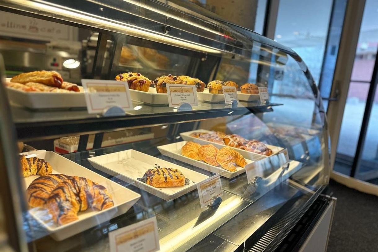 Glass display case with pastries on white trays.