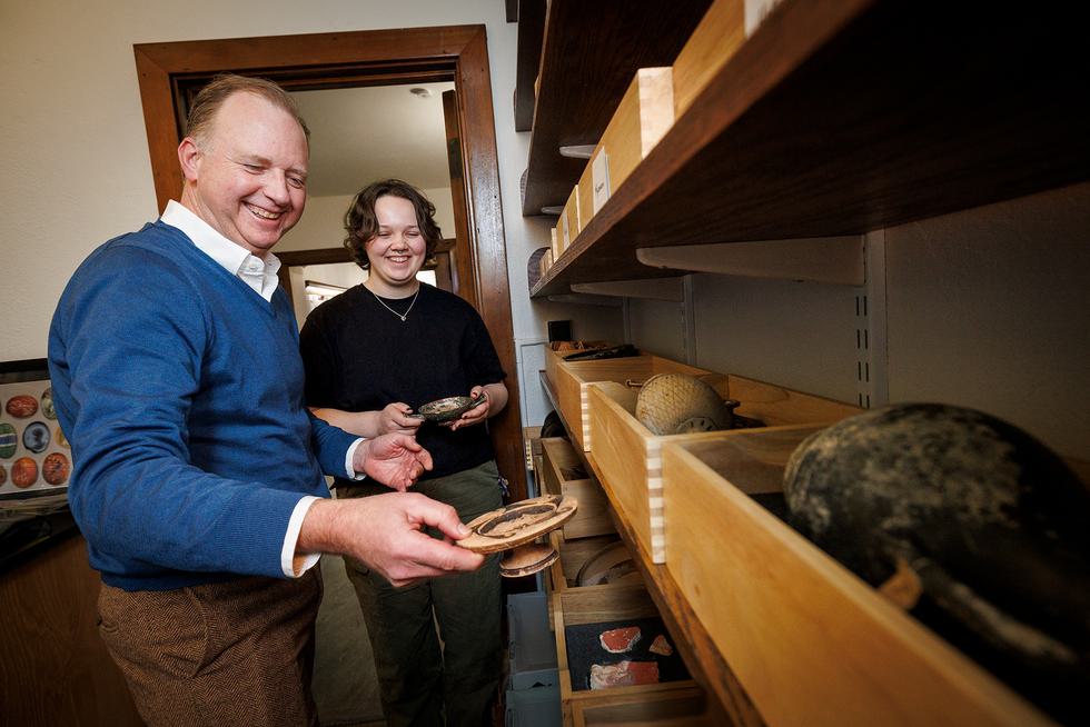 Classical studies professor Bryan Burns looks at artifacts with a student.