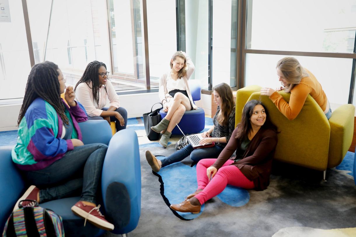 Five students engage in laughter around a computer.