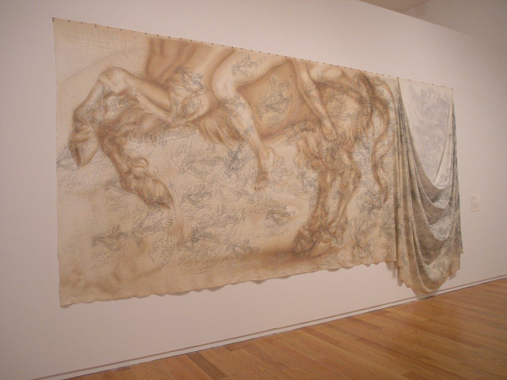 Canvas stretched and drapped across a large wall displays the lower half of a horse and rider