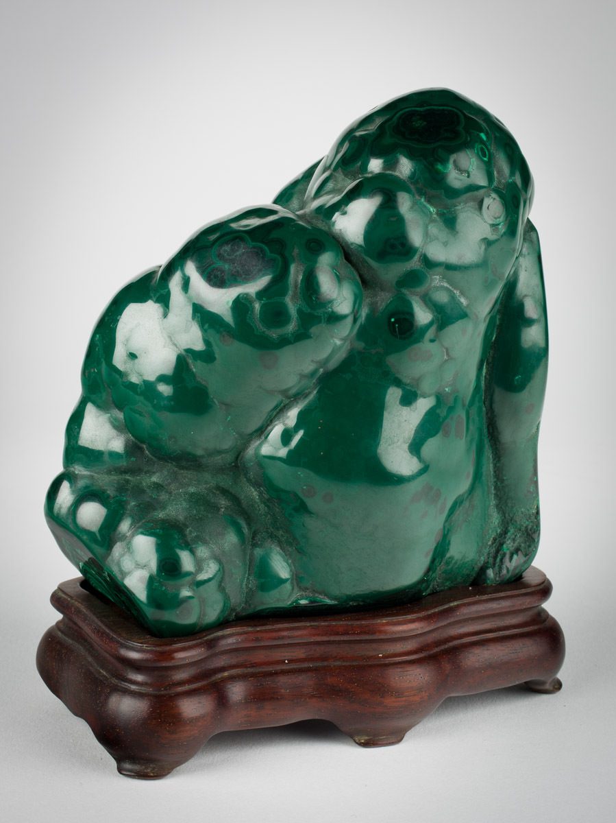 Photo caption: China, Malachite in the Shape of the Laughing Buddha, Modern period, 20th century, Mineral, copper carbonate hydroxide from Guangdong, Hubei, or Jiangxi provinces, 20th-century wooden stand, Northern style, Gift of Alan Helms 2017.148