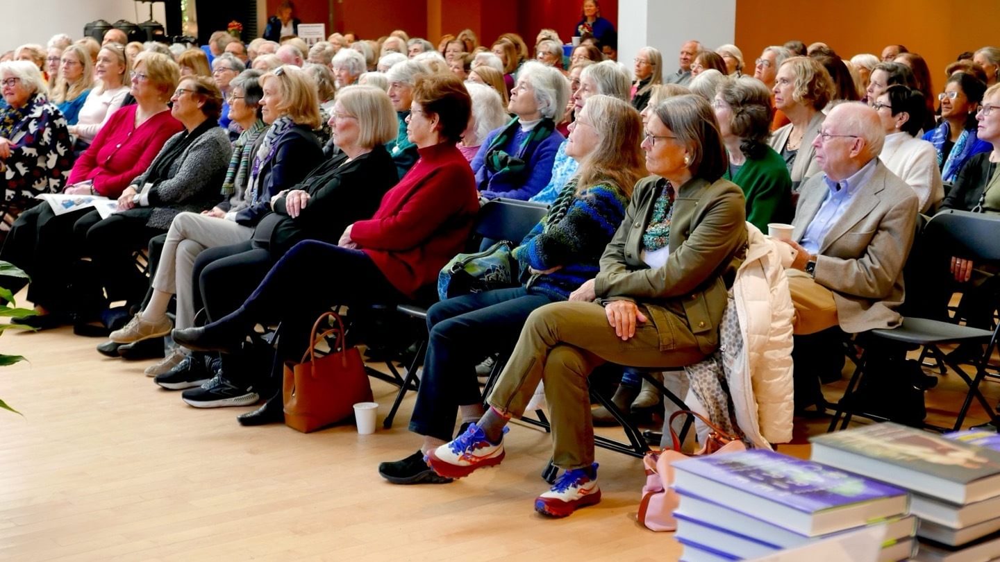 Seated audience with books in foreground