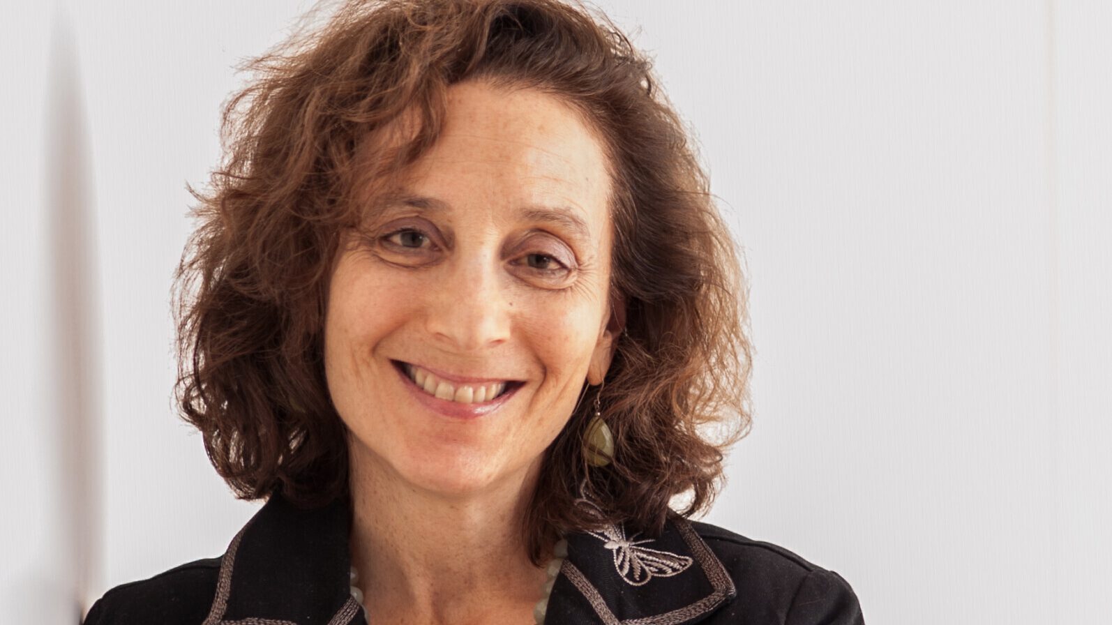 Peggy Levitt standing and smiling with arms crossed