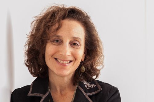 Peggy Levitt standing and smiling with arms crossed