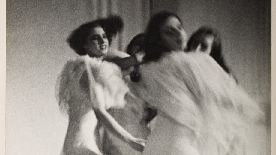 Black and white photo capturing dancers' movement in flowing white gowns