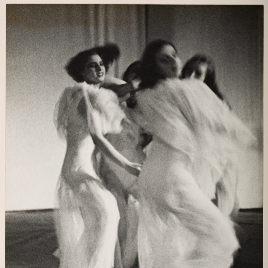 Black and white photo capturing dancers' movement in flowing white gowns