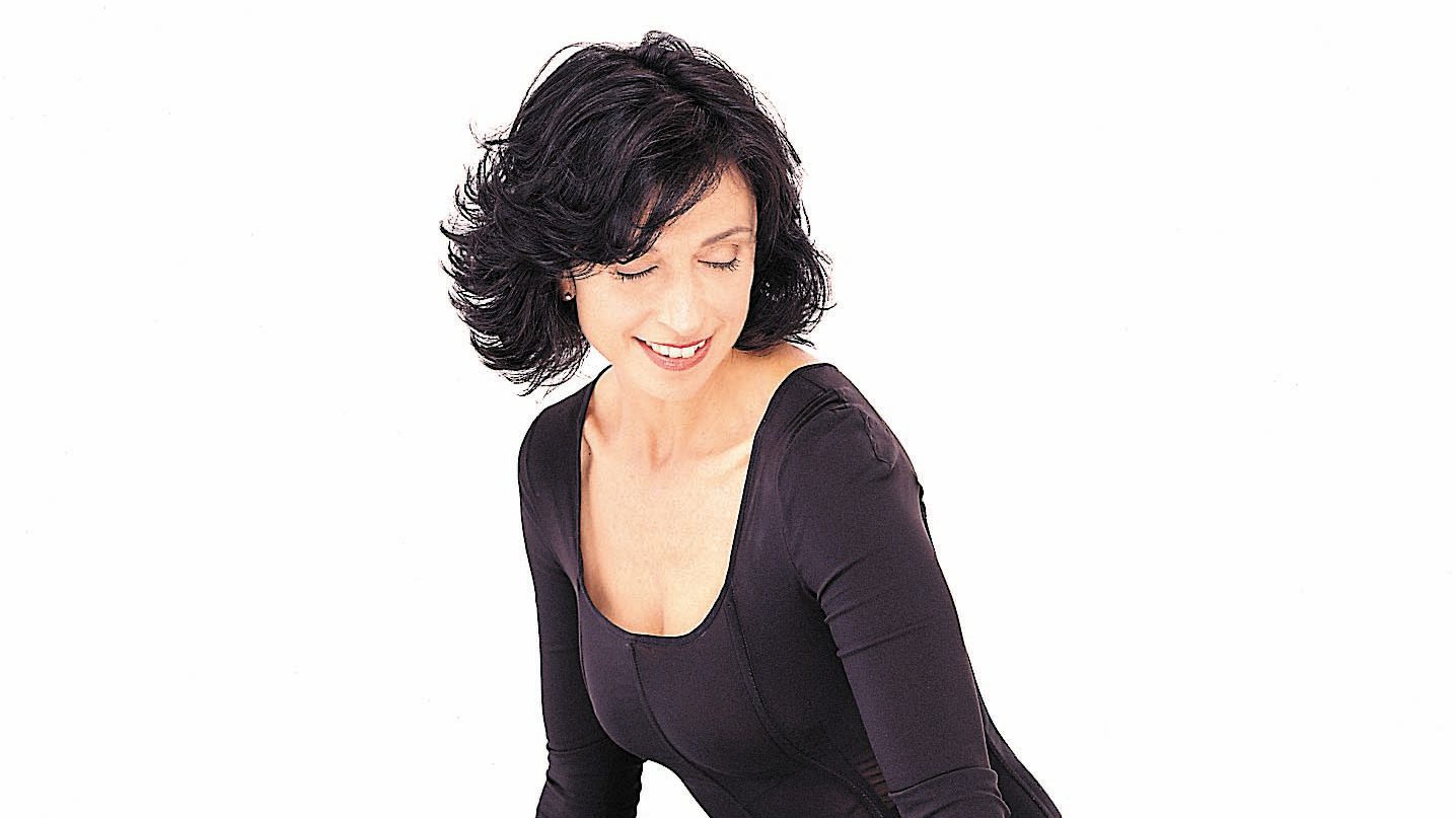 Suzanne Ciani seated on a piano wearing a black gown