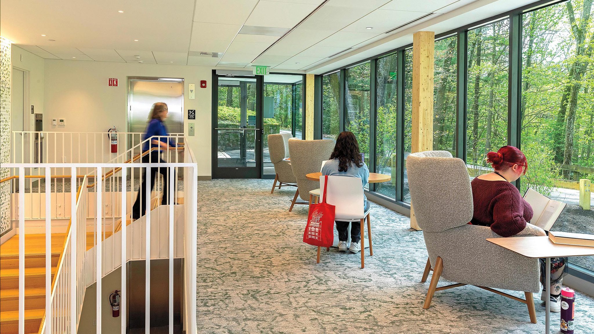A second-floor seating area with large windows overlooking trees