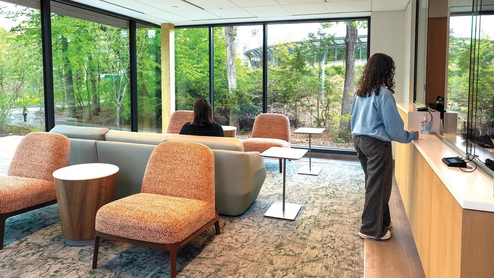 A reception area with modern seating and large windows looking out on trees