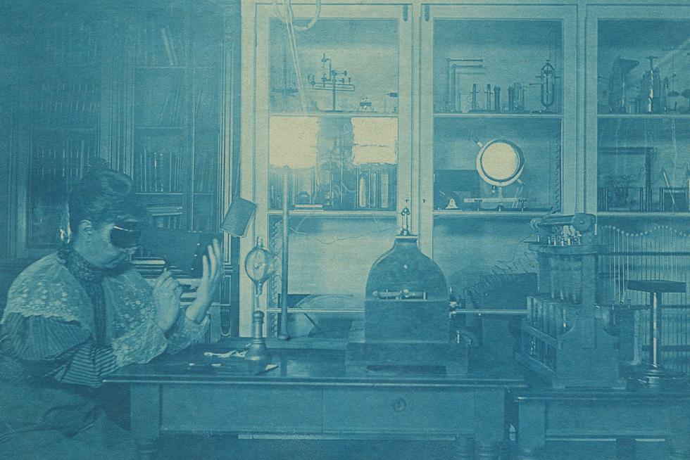 Sarah Frances Whiting examines the bones in her hand using a fluoroscope in Wellesley’s physics laboratory in 1896. A Crookes tube is on the table in front of her.