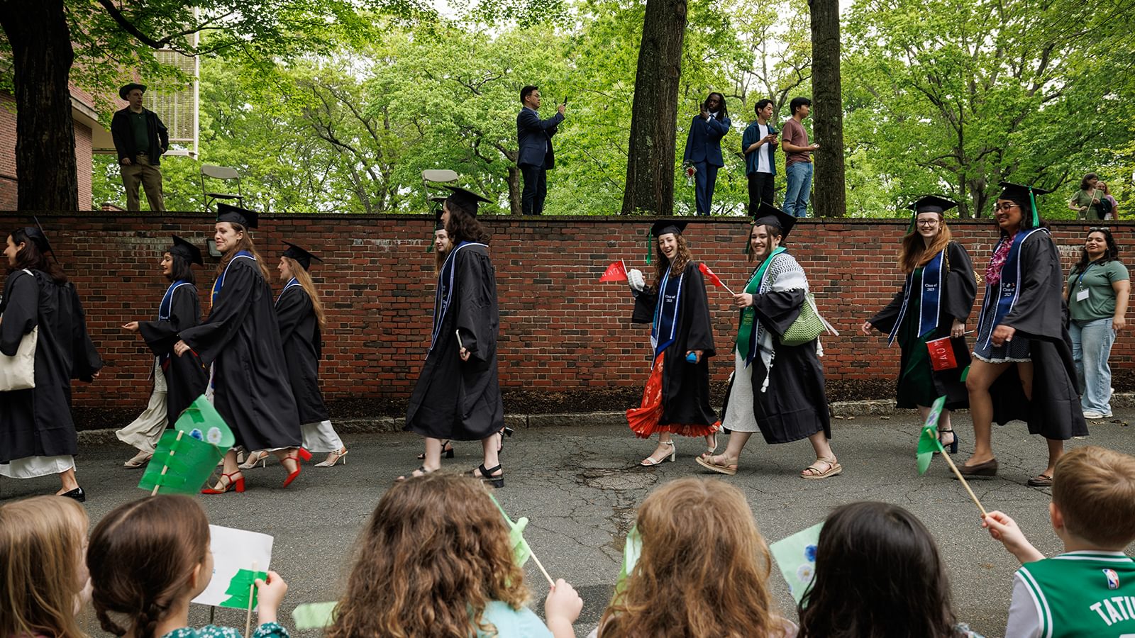 Students walk in the procession and wave at the crowd.