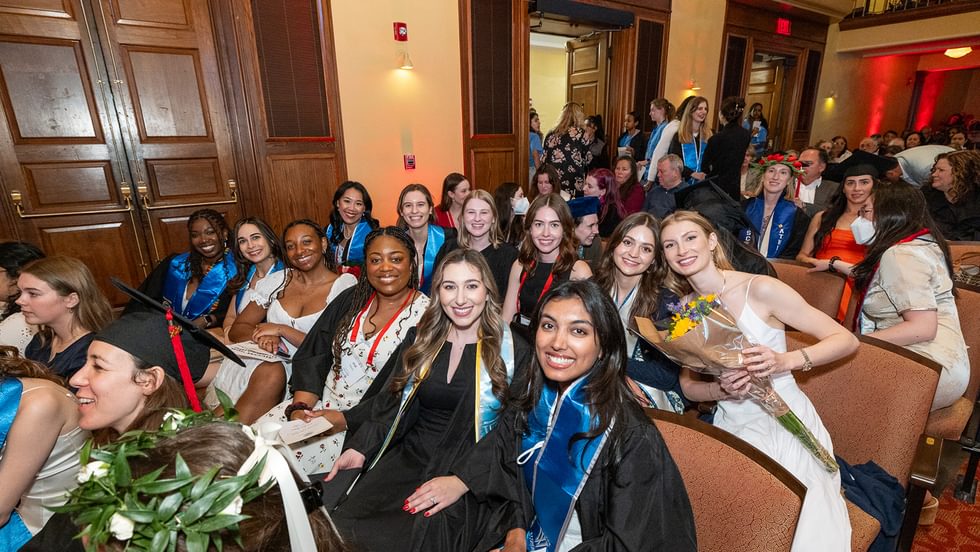 Class of 2020 smile for the camera as they sit together in Alumnae Ballroom