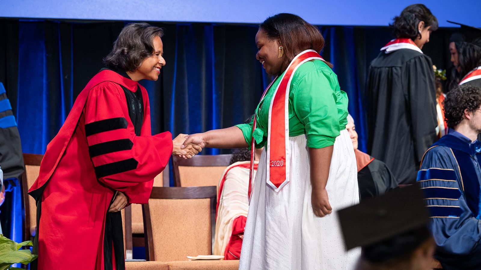 President Paula Johnson shakes hands with one of the members of the class of 2020 on stage.