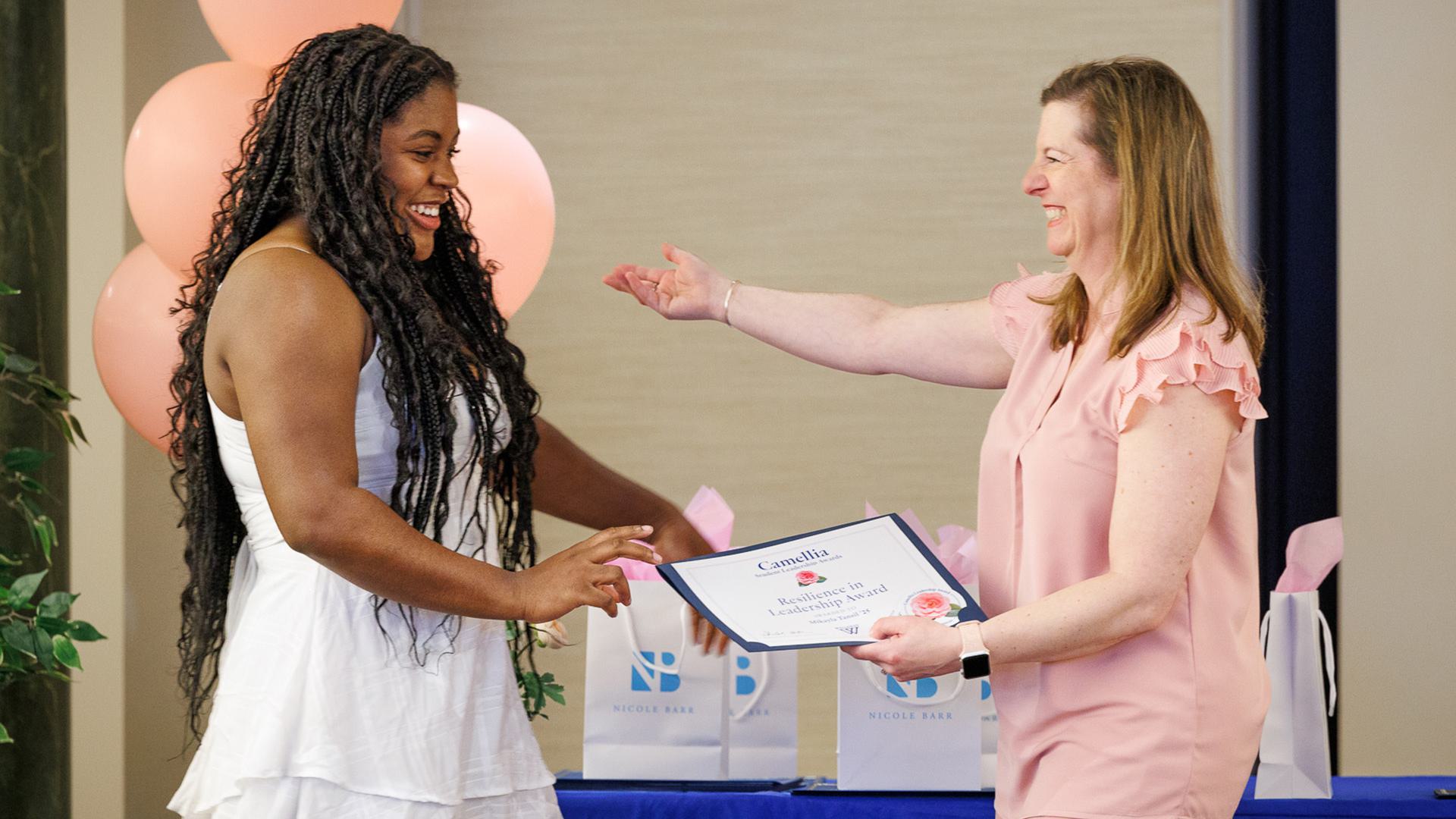 Dawn Montagna hold her arms out in greeting as Mikayla Tansil walks onto the stage to accept her award.