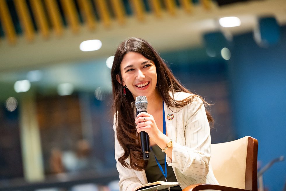 Ilinca Drondoe ’26 holds a microphone and smiles at someone out of range of the photo.