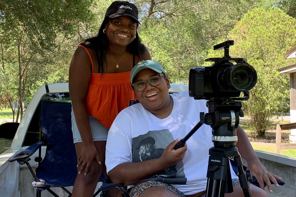 Catherine Sneed and their sister Meredith in the back of a truck with a camera.