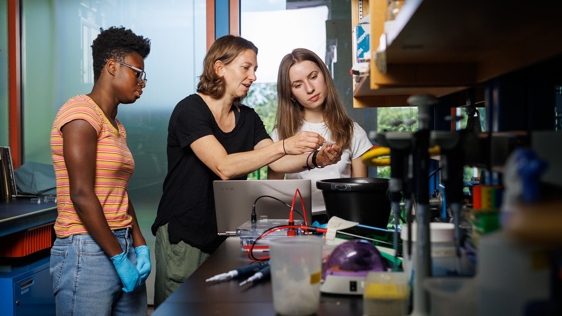 Two students and their professor work in a lab.