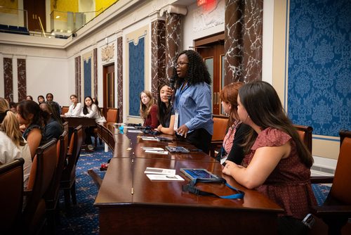 A student stands in the Edward M. Kennedy Institute for the United States Senate and speaks into a microphone.