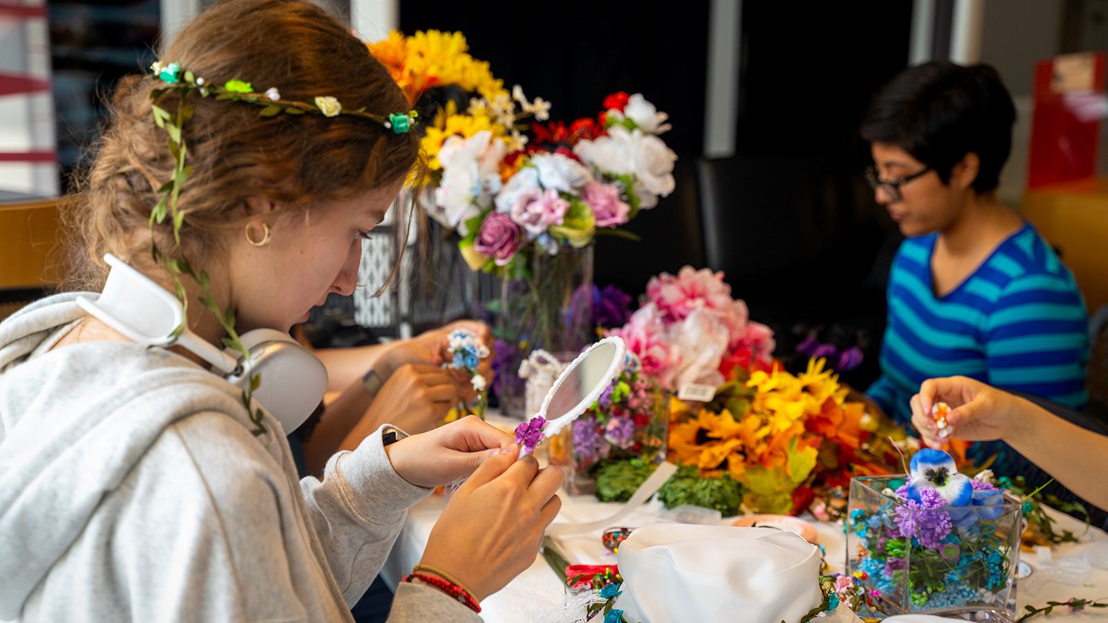 Students create wearable art using flowers and plants.