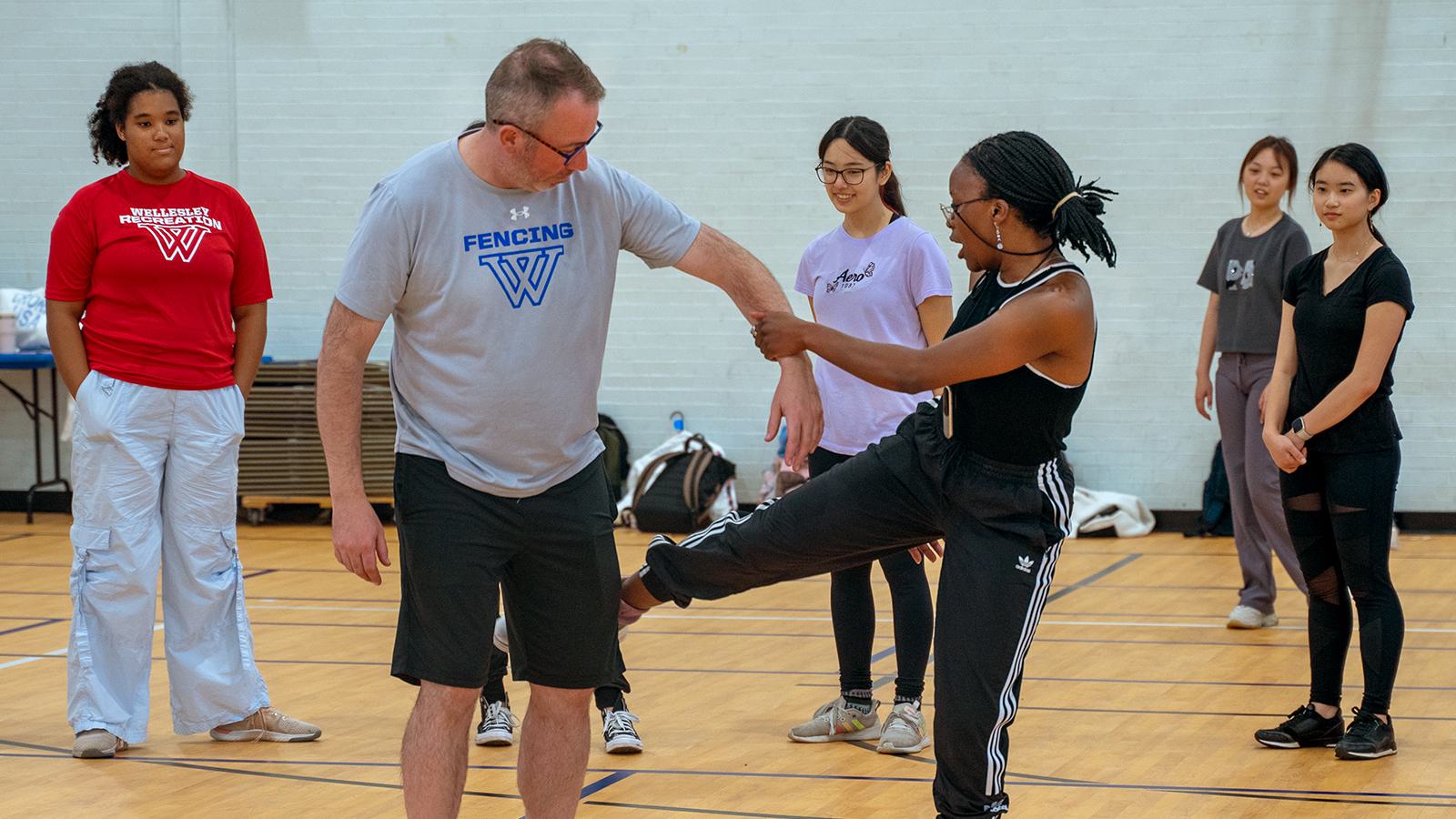 An actor feigns kicking the fencing coach during an acting workhop.