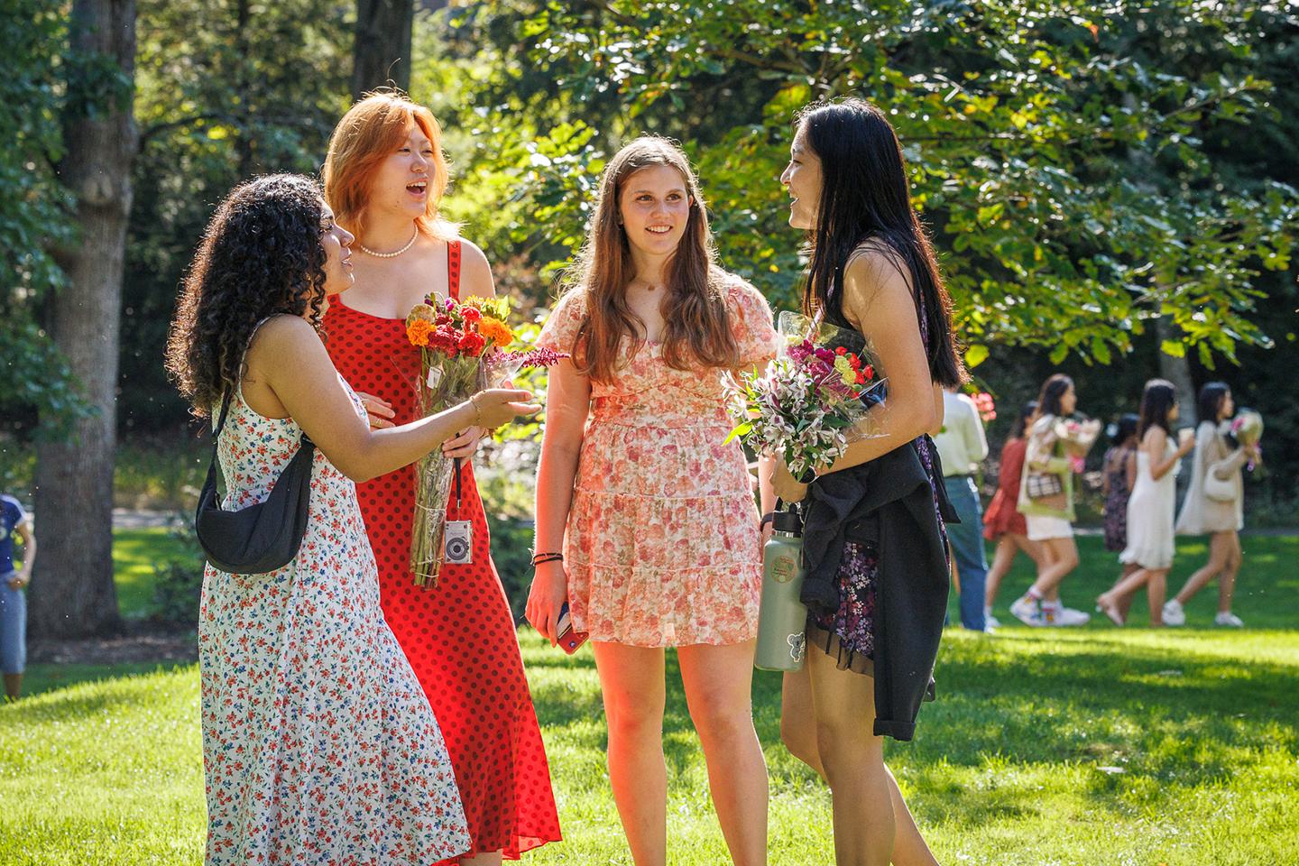Four students dressed for Flower Sunday stand and speak to each other
