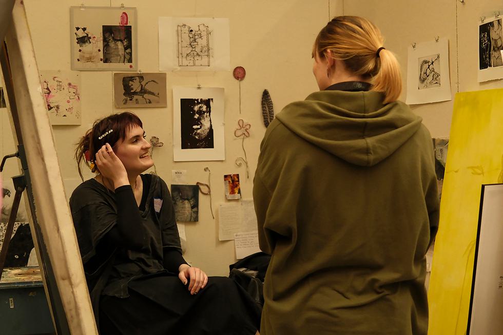 Hannah Albrecht ’25 (left) speaks with a visitor during open studio night.