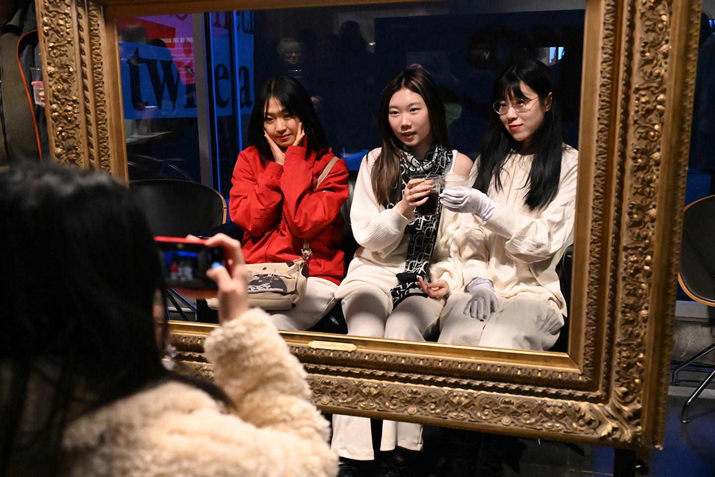 Three students pose for a photo within a gold frame.