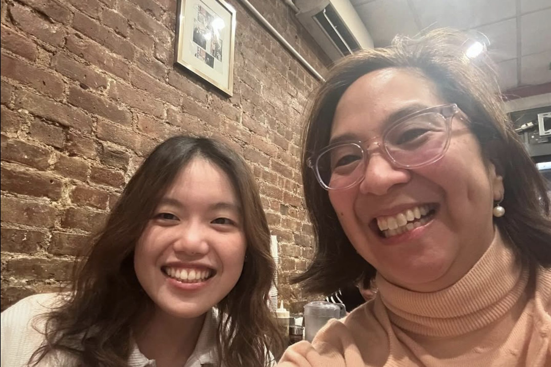 Two women, one in her twenties and the other middle age, smile into the camera for a selfie.