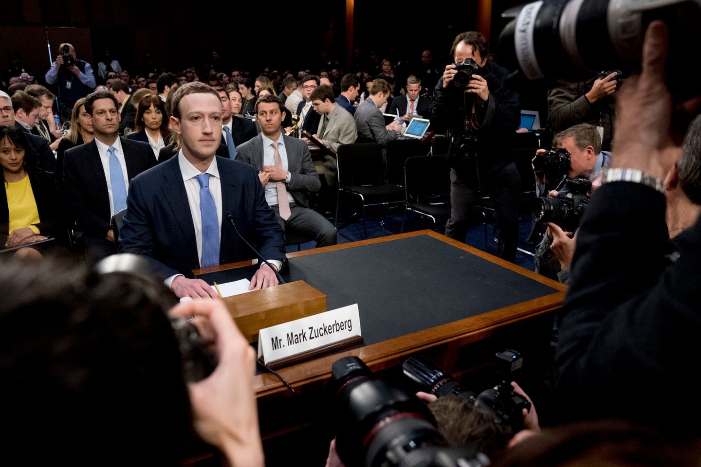 Mark Zuckerberg sitting at a table in Congress with media surrounding him