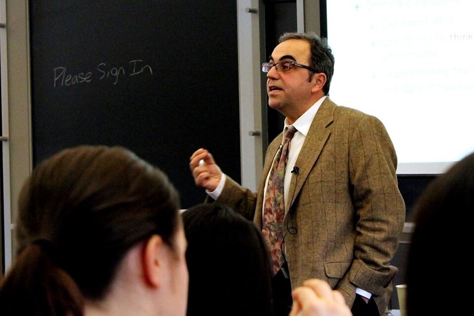 Professor Takis Metakas delivers a lecture at the front of a classroom.