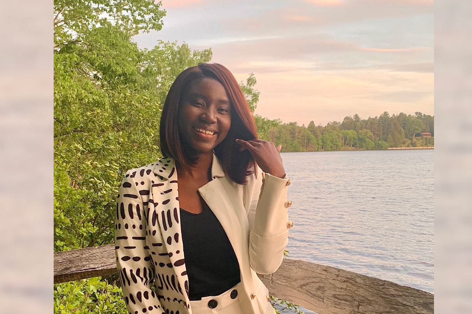 Adwoa Difie Antwi ’21 posing in front of Lake Waban with a sunset sky