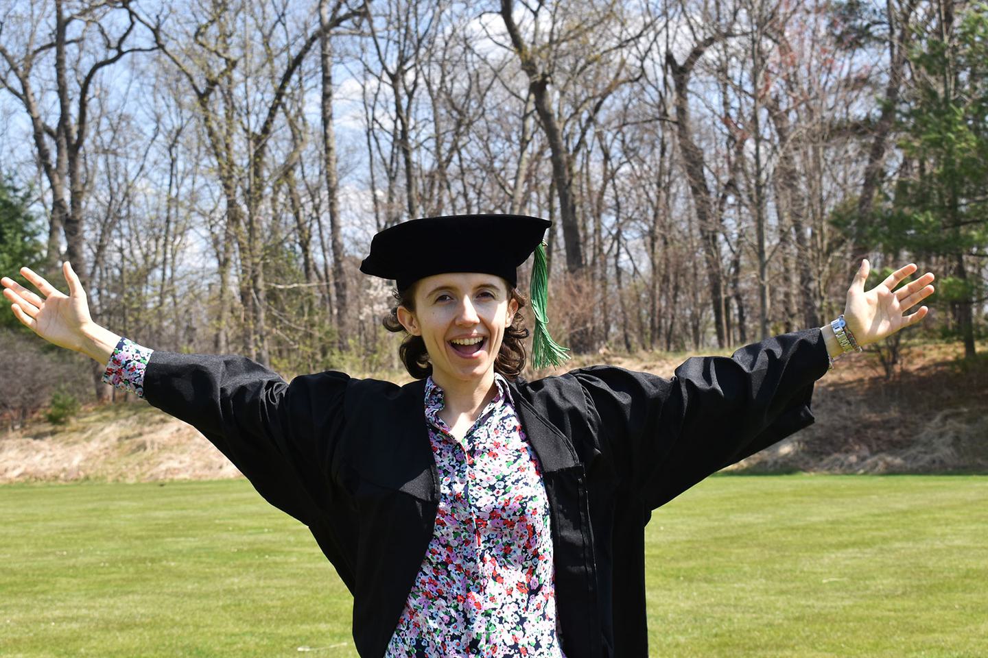 Liz Borecki ’21 wearing commencement robes standing on campus