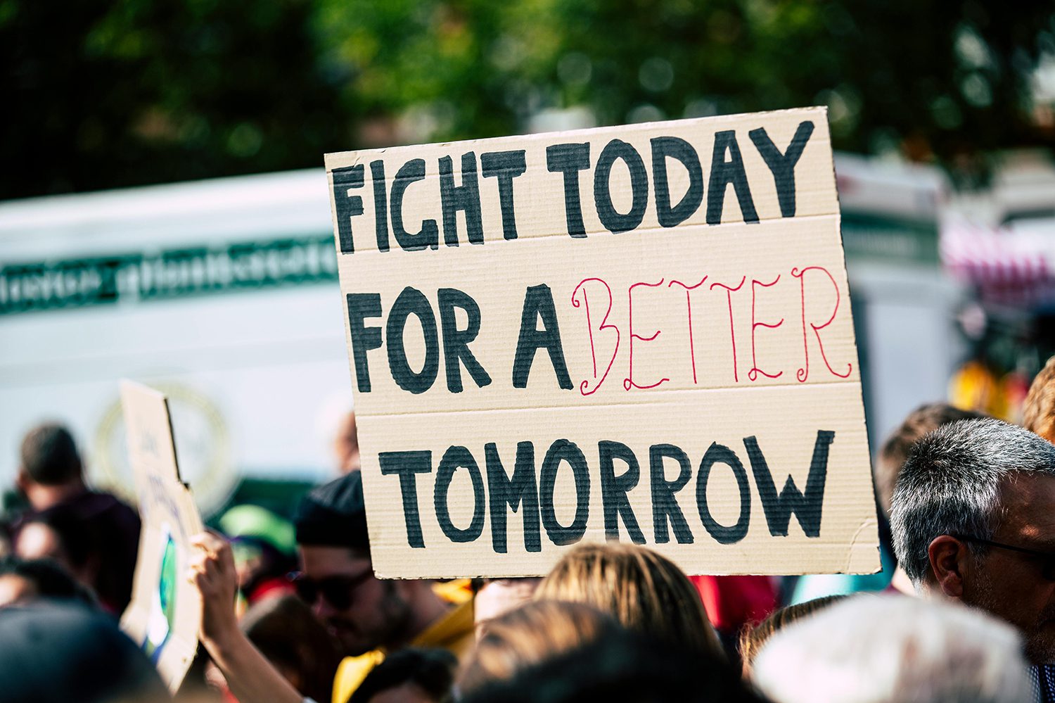 A sign at a protest reads fight today for a better tomorrow.