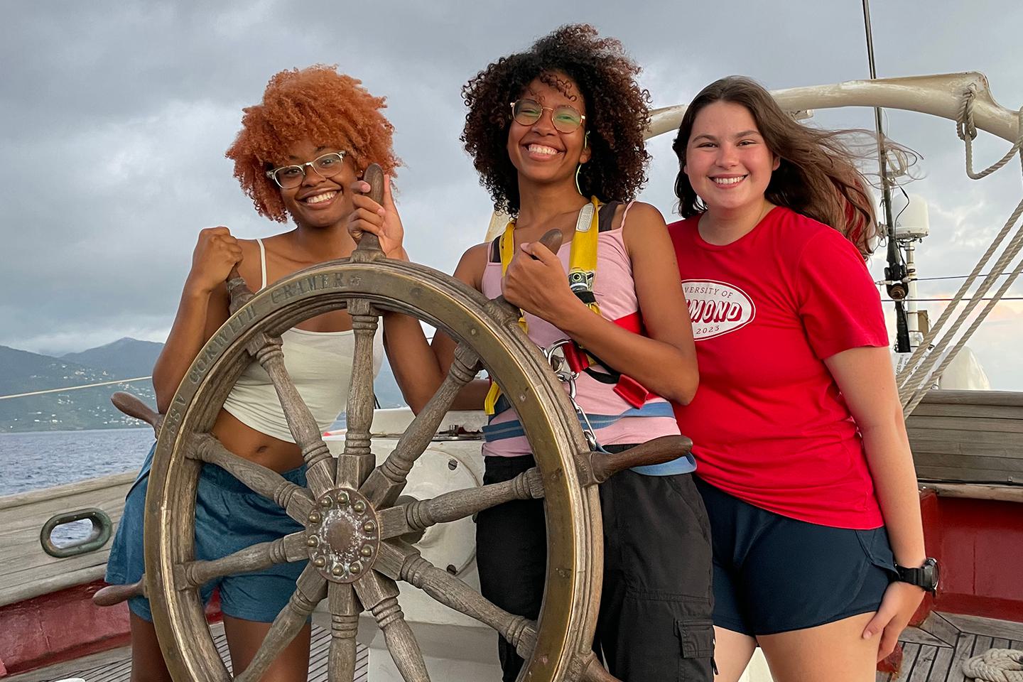 Amadi Mitchell ’23, Kyaralind Vasquez-Liriano ’23 and Macy Littell ’23 stand at the helm of the tall ship they worked on.