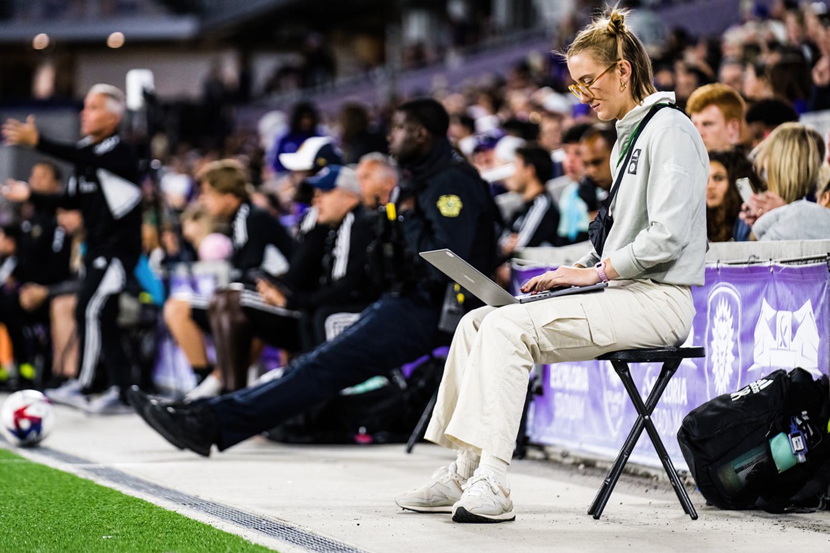 Olivia Reckley ’20 sits on the sidelines, working on her computer.