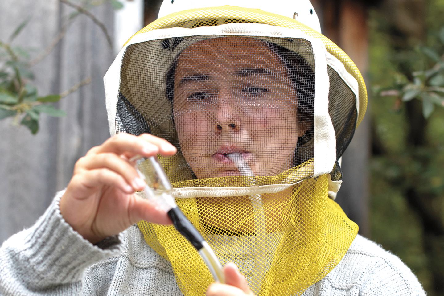 Marina Andreadis ’24 extracts a honey bee from the hive. A screen in the tube protects her from swallowing one.