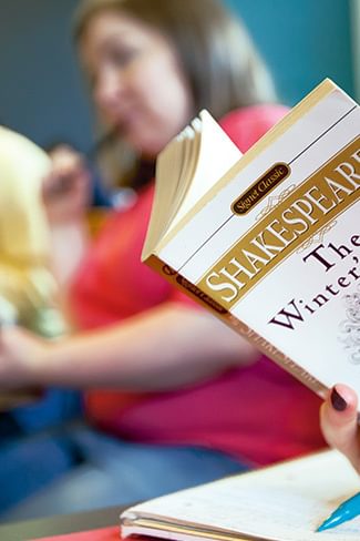 Wellesley College student reads a copy of The Winter's tale by Shakespeare in a classroom