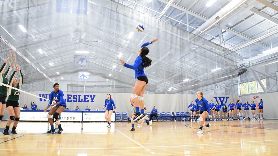Wellesley College volleyball team player hits a volleyball across the net to the opposing team
